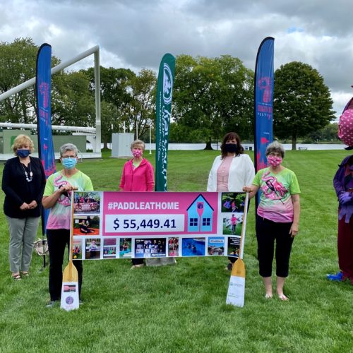 Volunteers outdoors with Dragin boat paddles and large cheque