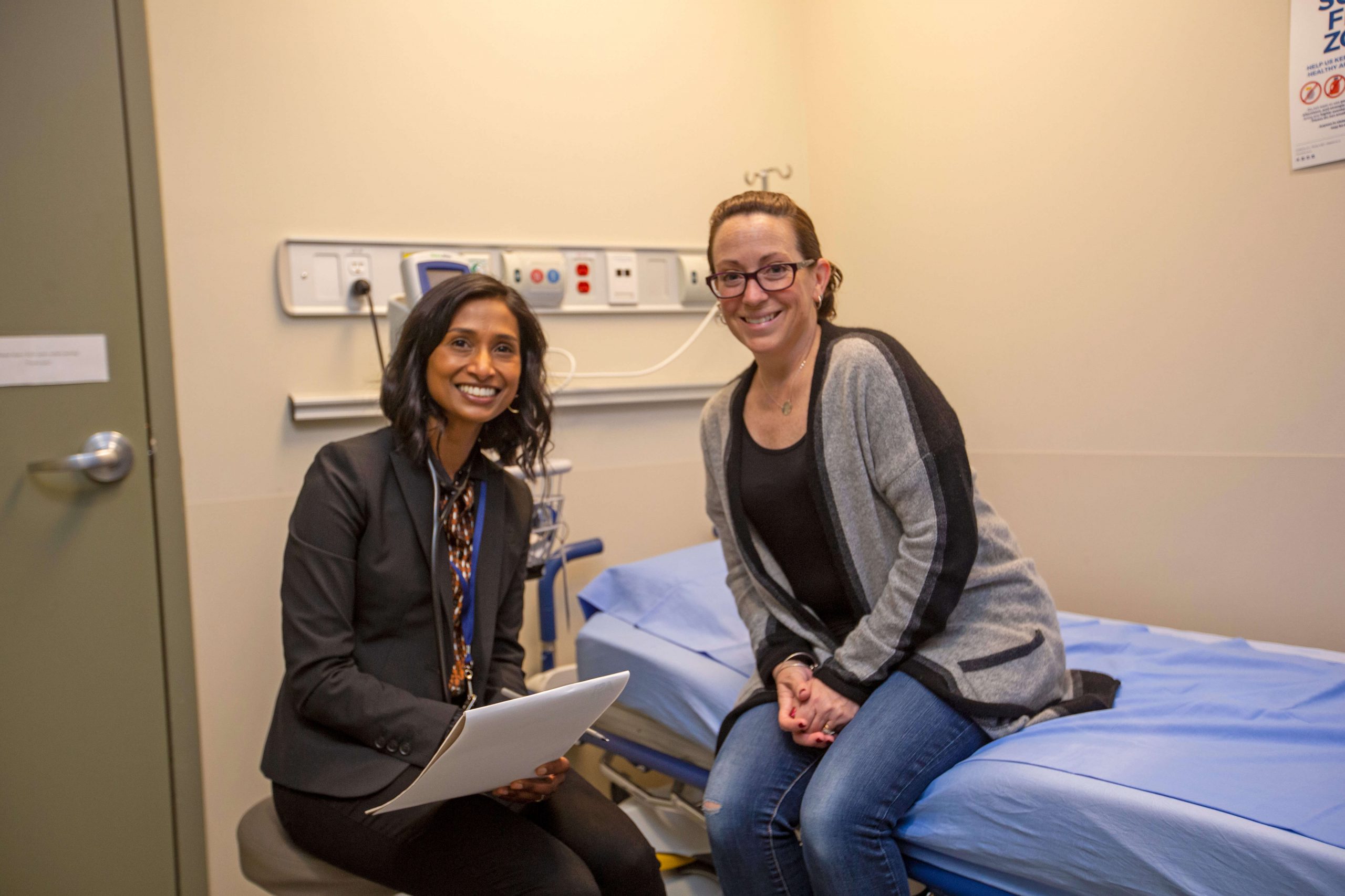 Doctor on stool and patient on bed smiling