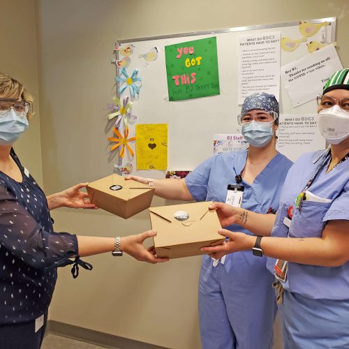 A manager gives two nurses gift boxes