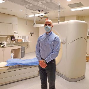 A radiologist stands in front of a CT scanner