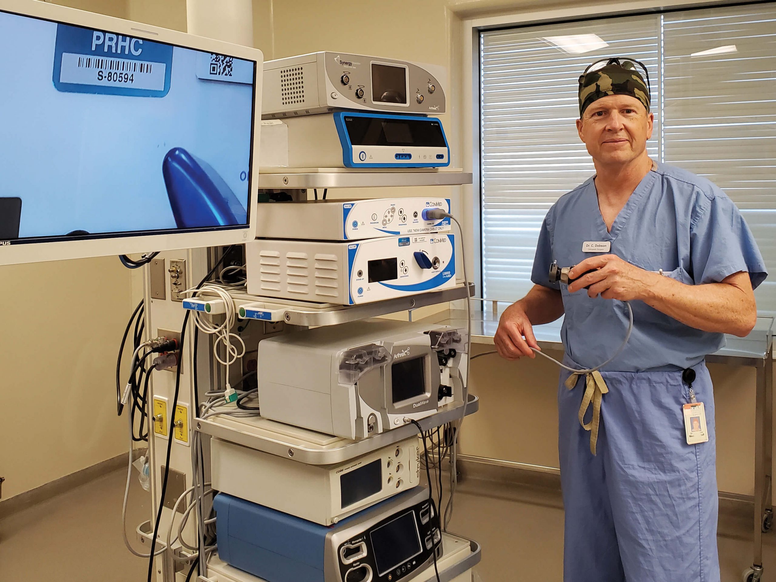A surgeon holds a camera beside surgical imaging equipment