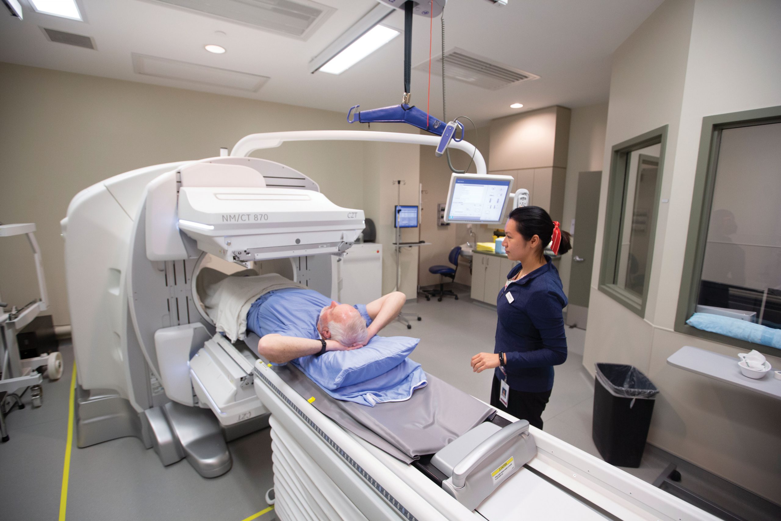 A medical radiation technologist demonstrates a SPECT/CT machine