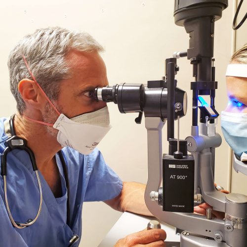 A doctor examines a patient's eyes using a slit lamp