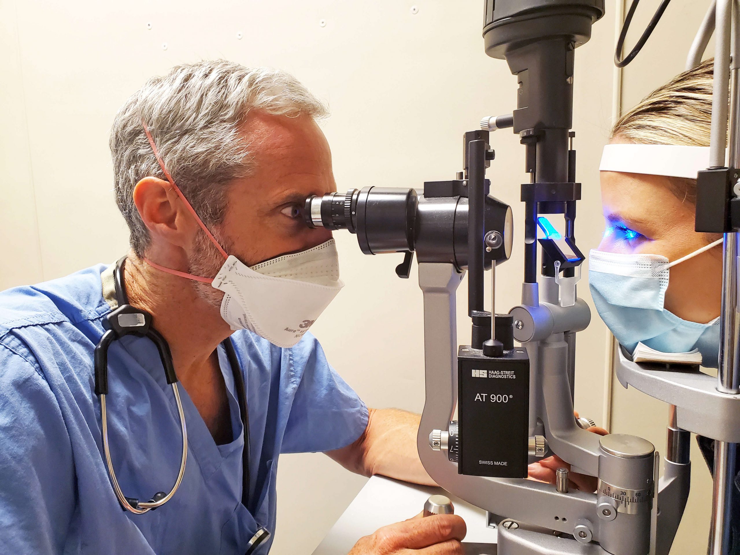 A doctor examines a patient's eyes using a slit lamp