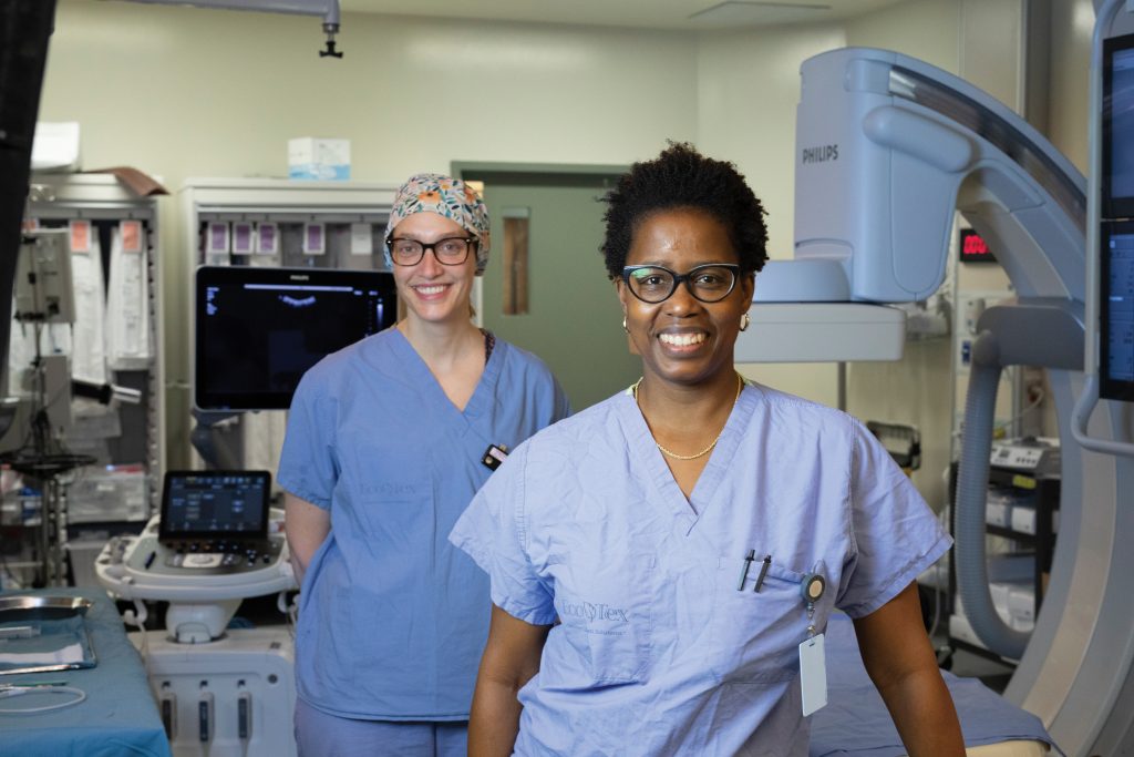 Two healthcare professionals stand inside a PRHC interventional radiology suite