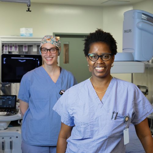 Two healthcare professionals stand inside a PRHC interventional radiology suite
